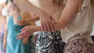 Massage des épaules entre participantes lors d'un stage de tantra