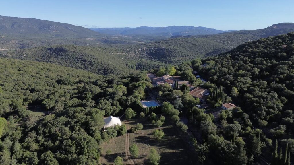 Le Hameau de l’Étoile vu du ciel : le hameau en pierre, la piscine et le grand chapiteau au milieu de la garrigue de l’Hérault. Photo Xavier Cailhol.